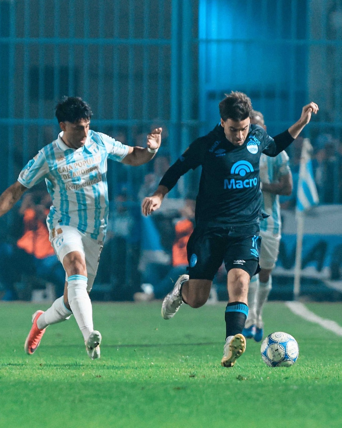 Delantero de Belgrano en carrera con la pelota, tribuna de fondo